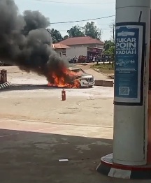 Sebuah mobil minibus warna putih terbakar hebat di area SPBU Tebing Tinggi, Kecamatan Tebo Tengah, Kabupaten Tebo, Jum’at (18/7/2025). Api tampak membakar bagian depan mobil disertai kepulan asap hitam tebal. Sebuah alat pemadam api ringan (APAR) terlihat diletakkan di dekat lokasi kejadian.(INJ/Ist)